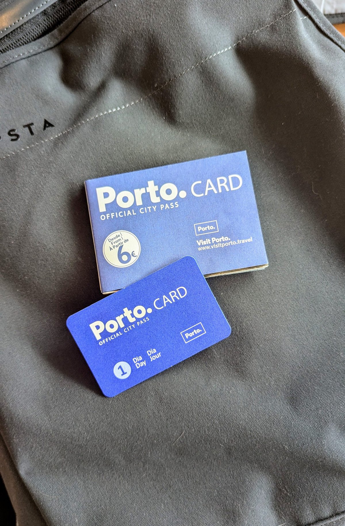 Close-up of a Porto Card package and card for the Porto city pass, laying on a black surface. The card indicates a 1 Day pass for public transportation in Porto, Portugal.