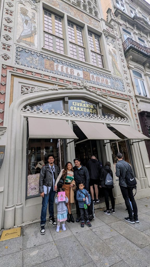 A group of people stand outside a historic ornate bookstore with a store entrance. The facade features decorative artwork.